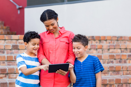 Smiling female teacher with students using digital tabletの写真素材