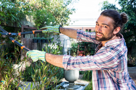 Portrait of happy hipster gardener using clippers at botanical gardenの写真素材