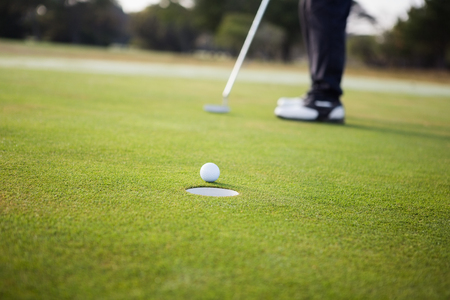 Close up of golf ball and a hole on a field