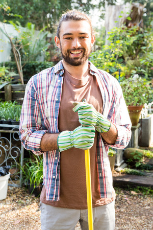 Portrait of young hipster gardener with tool at community gardenの写真素材
