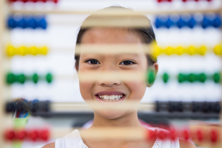 Portrait of girl in front of abacus in classroom