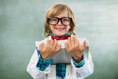 Portrait of boy dressed as scientist standing with parcel in classroom