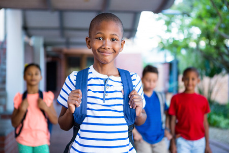 Portrait of schoolboy with classmates in background at school corridorの写真素材