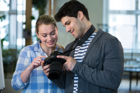 Happy male photographer showing picture to female colleague at creative officeの写真素材
