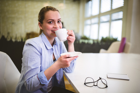 Portrait of smiling businesswoman having coffee in meeting roomの写真素材