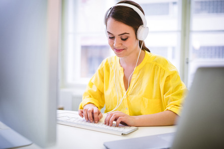 Happy young female executive typing on keyboard at creative office