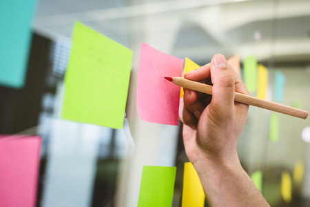 Cropped image of businessman writing on sticky notes in creative officeの写真素材