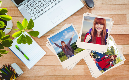 Smiling hipster woman with a travel bag taking selfie against business desk with laptop and colors...