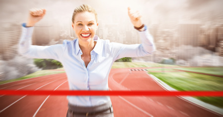 Successful businesswoman raising arms against composite image of racetrack in cityの写真素材