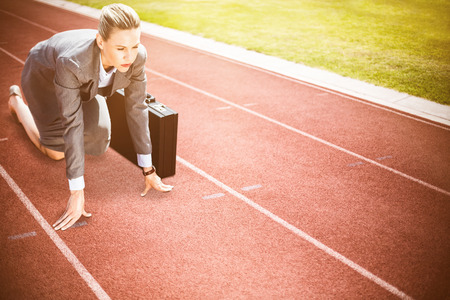 Businesswoman in starting position against focus on track on a sunny dayの写真素材