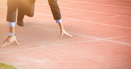 Businessman in the starting blocks against view of a running track