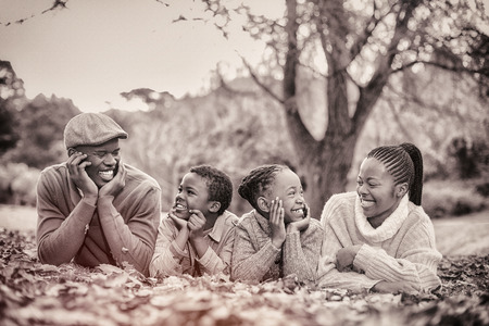 Portrait of a young smiling family lying in leaves on an autumns day