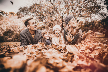 Smiling young family throwing leaves around on an autumns day