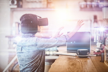 Young woman using the virtual reality headset while working on computerの写真素材