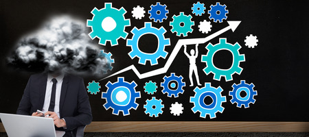 Happy businessman with laptop using smartphone against blackboard on wallの写真素材