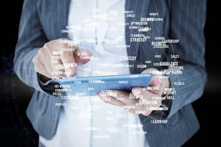 Businesswoman using her tablet against shiny spiral of binary codeの写真素材
