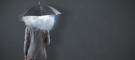 Businessman standing under umbrella against grey backgroundの写真素材