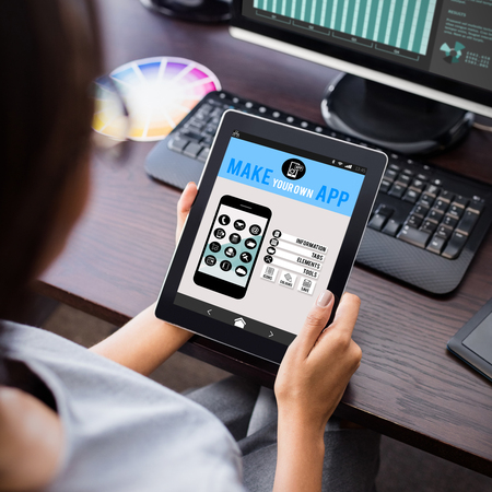 Make your own app smartphone against woman watching her tablet computerの写真素材
