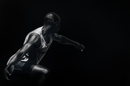 Rear view of sportsman throwing a discus against black background