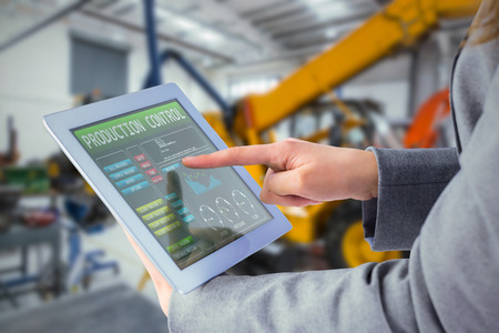 Businesswoman using a tablet pc against mechanic workshopの写真素材