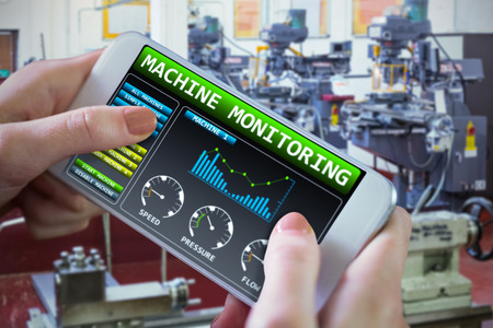 Hand holding smartphone against image of machinery