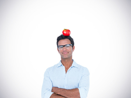 Confident man standing with arms crossed against red appleの写真素材