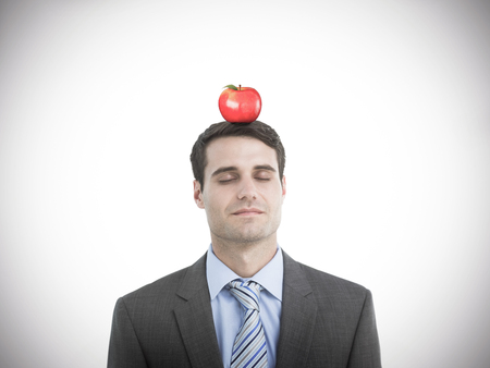 Handsome businessman with eyes closed against red appleの写真素材