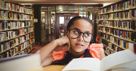 Young girl day dreaming by book at table against entrance of the college library