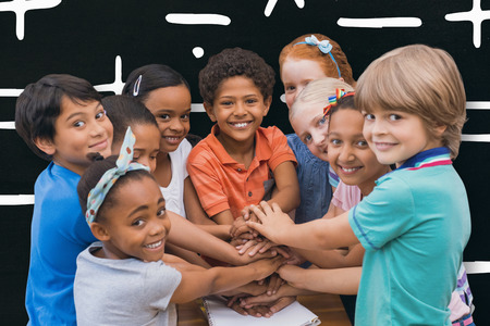 Cute pupils smiling at camera in classroom against black