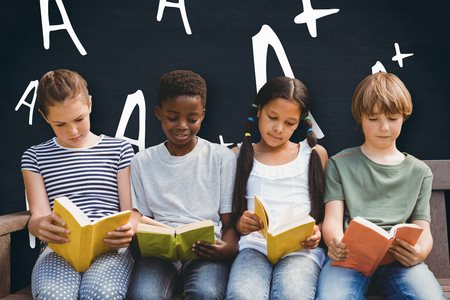 Children reading books at park against blackboardの写真素材