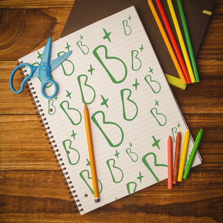 B plus doodle against notepad on student deskの写真素材