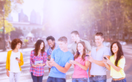 Four laughing friends sending texts on their phones against picture of a city