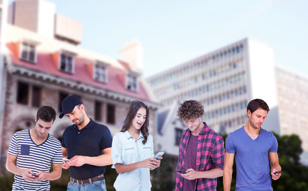 Handsome man text messaging through smart phone against buildings against sky in cityの写真素材