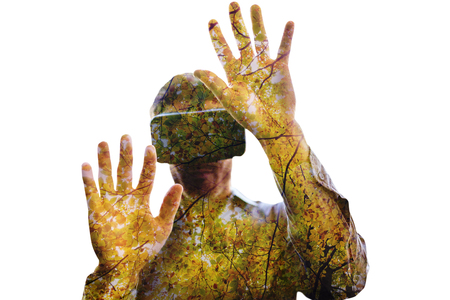 Man using a virtual reality device against branches and autumnal leavesの写真素材