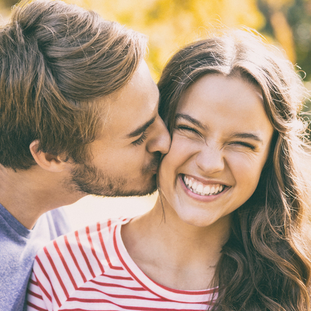 Cute couple kissing in the park on a sunny dayの写真素材