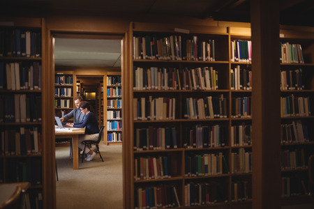 Mature students working together with laptop in college library