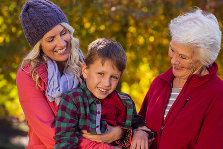 Happy boy with mother and grandmother at park during autumnの写真素材