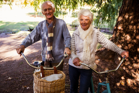 Senior couple holding their bike in a parkの写真素材