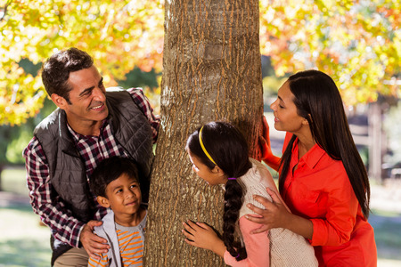 Playful happy family standing by tree at parkの写真素材
