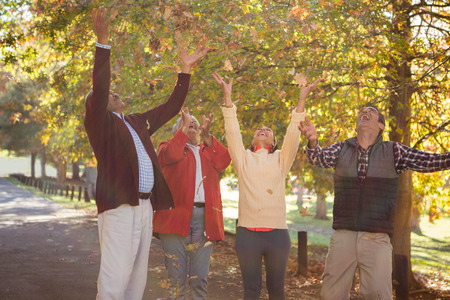 Family throwing autumn leaves while enjoying at park