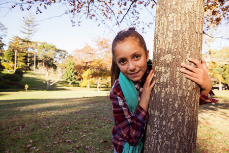 Portrait of happy girl hugging tree in parkの写真素材