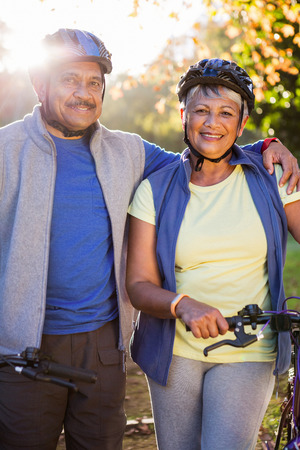Portrait of mature couple holding cycling helmet in a parkの写真素材