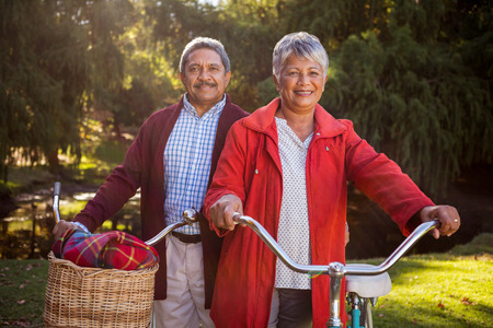 Portrait of happy mature couple with bicycle at parkの写真素材