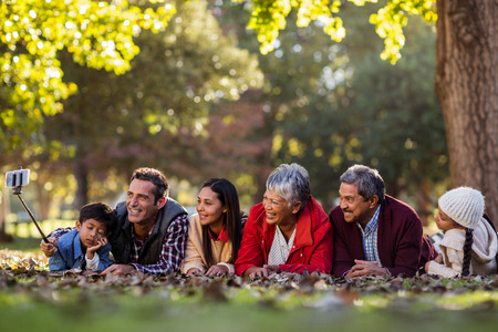 Man with happy family taking selfie against trees at parkの写真素材