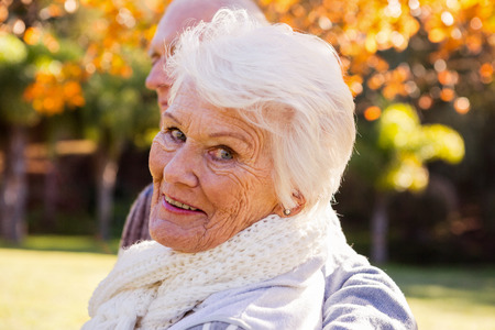 Portrait of a senior woman with her husband in background in a park