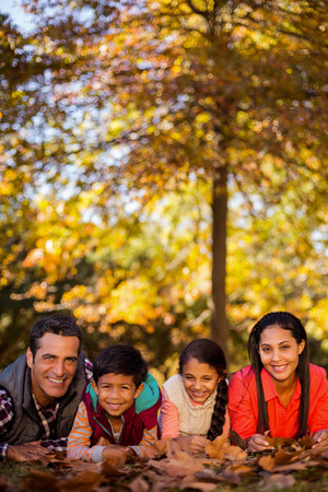 Portrait of happy family lying on field at park during autumnの写真素材