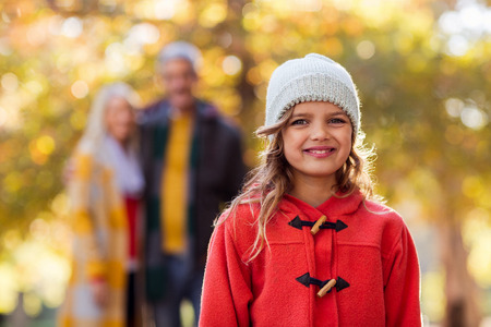 Portrait of smiling girl with family in background at park