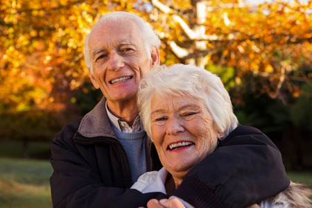 Portrait of happy senior couple embracing at park during autumn
