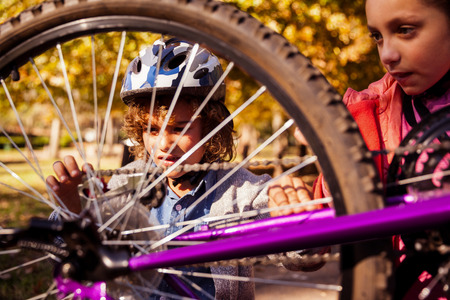 Siblings repairing mountain bike in parkの写真素材