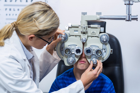 Female optometrist examining young patient on phoropter in ophthalmology clinicの写真素材